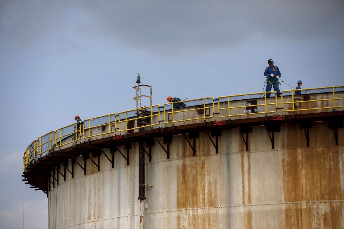 <i>Cole Burston/Bloomberg/Getty Images</i><br/>The world must limit global warming to 1.5 degrees Celsius above pre-industrial levels to limit climate crisis. Workers here stand atop a storage tank at an Imperial Oil Ltd. refinery in Sarnia