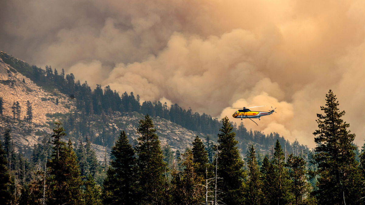 <i>Noah Berger/AP</i><br/>A helicopter flies over Wrights Lake while battling the Caldor Fire in Eldorado National Forest