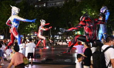 People watch sculptures of Ultraman and a monster outside a shopping center on July 17 in Chongqing