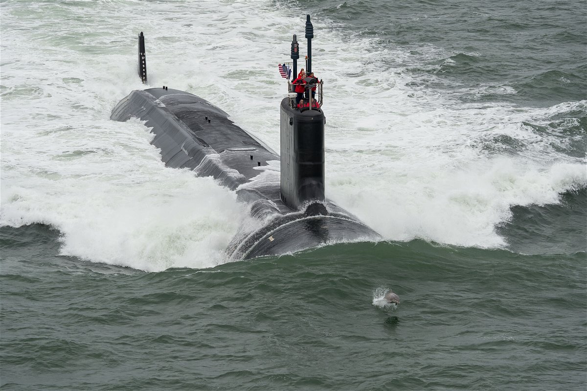<i>U.S. Navy photo courtesy of Huntington Ingalls Industries by ChrisOxley/Released</i><br/>A dolphins swims in front of Navy's newest submarine