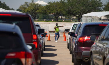 An election worker guides voters in cars at a drive-through mail ballot drop-off site at NRG Stadium in Houston