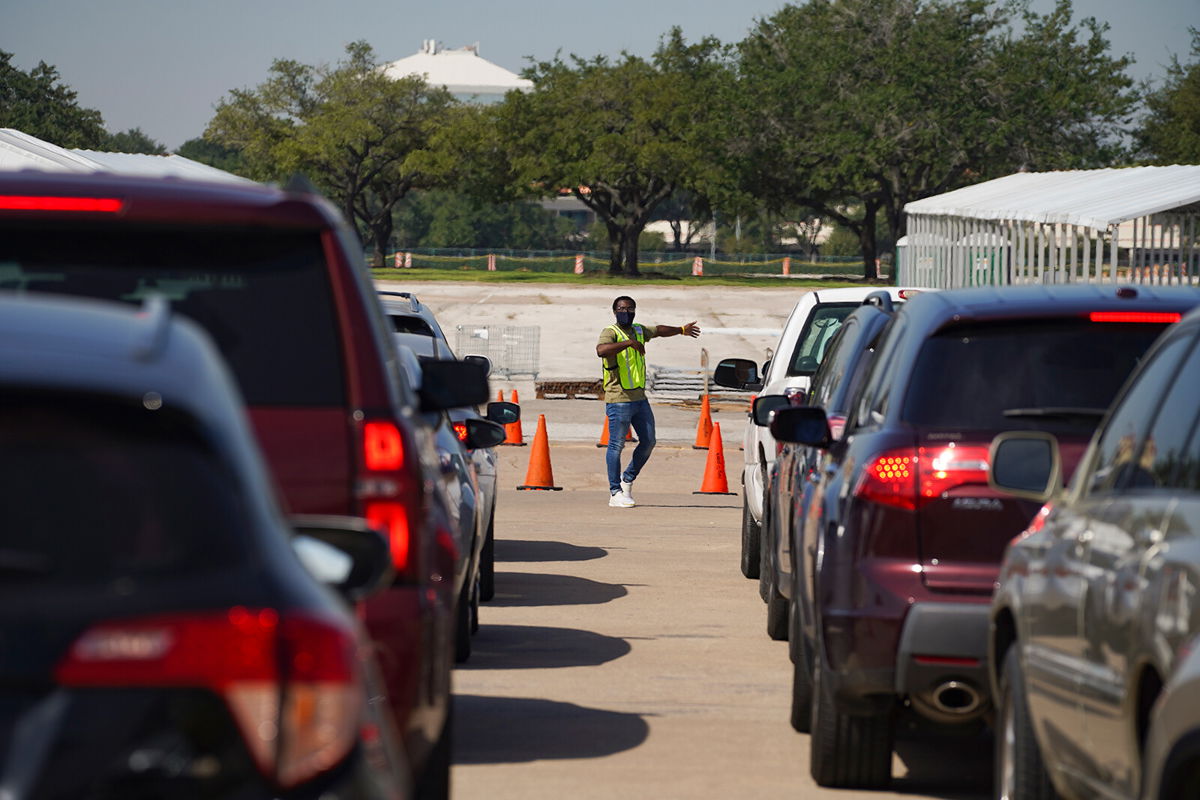 <i>Go Nakamura/Getty Images</i><br/>An election worker guides voters in cars at a drive-through mail ballot drop-off site at NRG Stadium in Houston