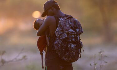 An exhausted Haitian father cradles his son on the Mexican side of the Rio Grande from Del Rio