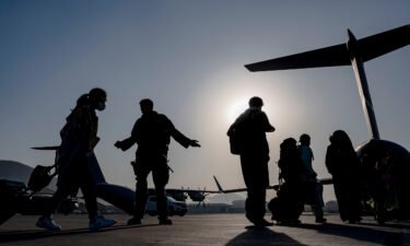 US Air Force airmen guide evacuees aboard a US Air Force C-17 Globemaster III at Hamid Karzai International Airport in Kabul
