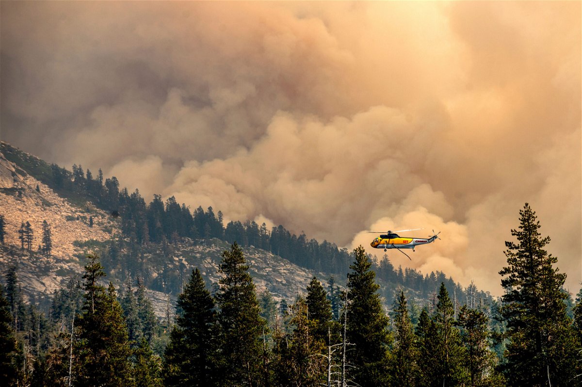 <i>Noah Berger/AP</i><br/>Lighter winds could bring relief to firefighters battling the Caldor Fire. A helicopter here battles the Caldor Fire in Eldorado National Forest