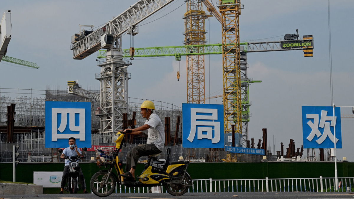 <i>NOEL CELIS/AFP/Getty Images</i><br/>Workers drive their motorbikes in front of the under-construction Guangzhou Evergrande football stadium in Guangzhou