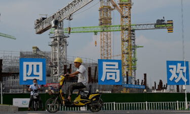 Workers drive their motorbikes in front of the under-construction Guangzhou Evergrande football stadium in Guangzhou