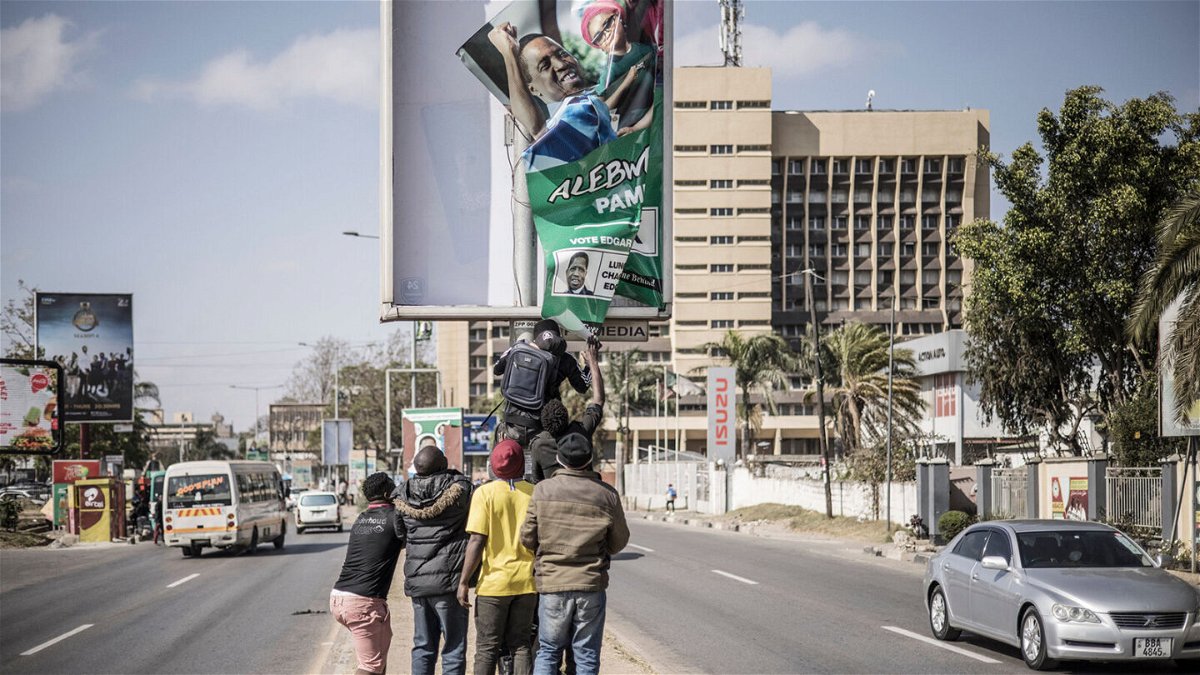 <i>Marco Longari/AFP/Getty Images</i><br/>Supporters of Hakainde Hichilema remove a poster of former president Edgar Lungu from a pole in Lusaka