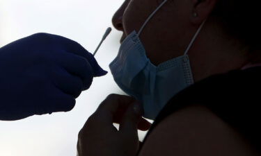 A person receives a COVID-19 test from EMT Christopher Linares at a Blue Med Consultants facility on September 9