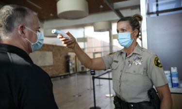 A Sheriff's deputy takes an employee's temperature as at Las Colinas women's Detention Facility in Santee