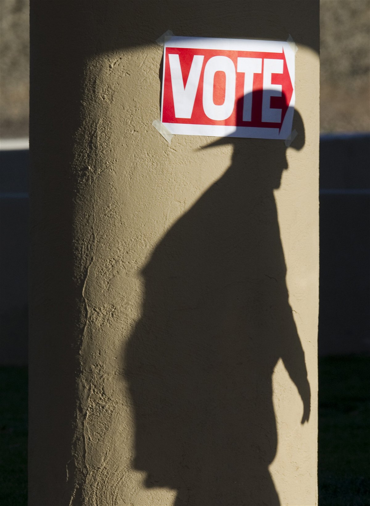 <i>DON EMMERT/AFP/AFP via Getty Images</i><br/>A shadow of a man wearing a cowboy hat falls on a pillar as he enters the polling place at Wickenburg Community Center on February 28