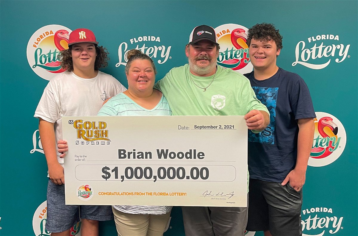 <i>From Florida Lottery/Twitter</i><br/>Auto repair shop owner Brian Woodle poses with a check after winning $1 million from a scratch-off Florida Lottery game.