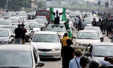 A demonstrator raises a Nigerian flag from a car during a motorcade to mark the one-year anniversary of the #EndSARS protest at the Lekki toll gate in Lagos