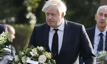 Britain's Prime Minister Boris Johnson carries a floral tribute on arrival at the scene of the fatal stabbing of Conservative British lawmaker David Amess