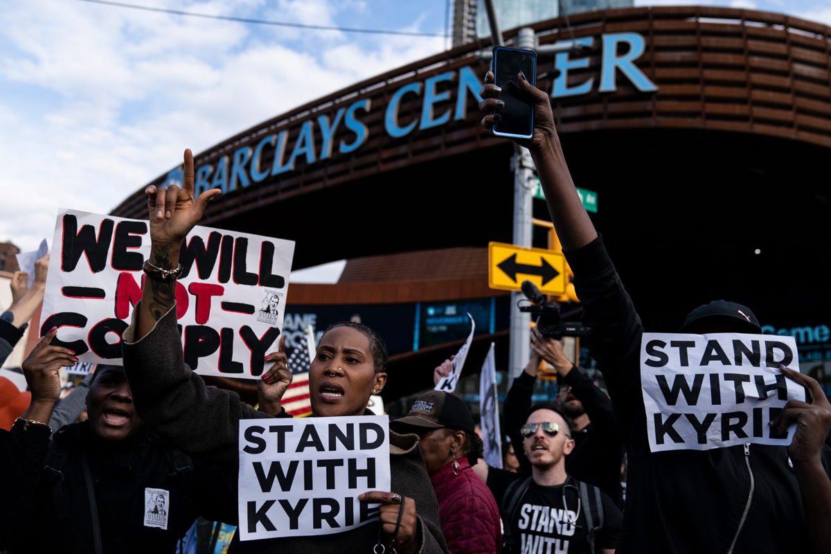 <i>John Minchillo/AP</i><br/>Protesters rallying against COVID-19 vaccination mandates and in support of basketball player Kyrie Irving gather in the street outside the Barclays Center before an NBA basketball game between the Brooklyn Nets and the Charlotte Hornets