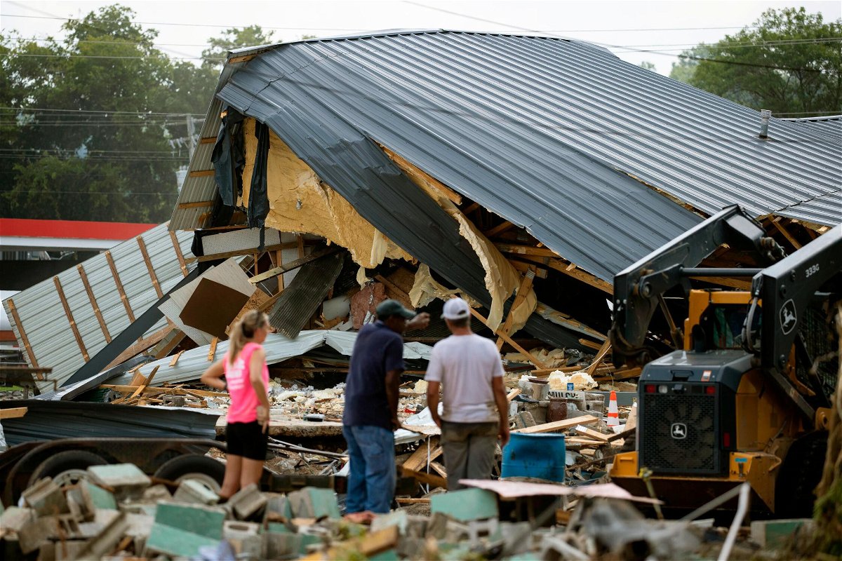 <i>Brett Carlsen/Getty Images</i><br/>People watch cleanup efforts after buildings were destroyed by flooding in August in Waverly