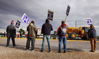 At truck hauls a piece of John Deere equipment from the factory past workers picketing outside of the John Deere Davenport Works facility on October 15 in Davenport