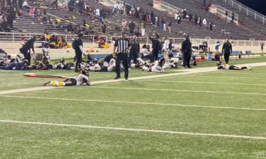 Players lie on the field as they take cover during a football game at Ladd-Peebles Stadium in Mobile