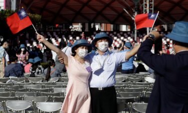 A couple take a photo with Taiwan national flags during National Day celebrations in front of the Presidential Building in Taipei