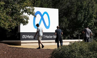 Facebook employees take a photo in front of new Meta Platforms Inc. sign outside the company headquarters in Menlo Park
