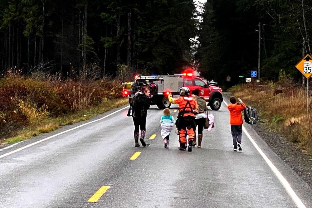 A Coast Guard rescue swimmer escorts multiple people who were evacuated from their residences during a flood near Forks, Wash.