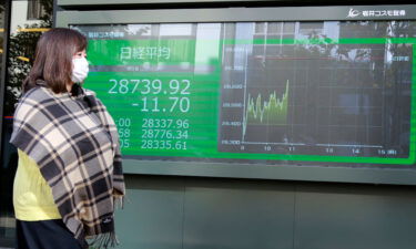 A woman walks by an electronic stock board of a securities firm in Tokyo