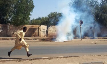 A Sudanese opponent of the military coup runs from tear gas launched by security forces during a protest in city of Umdurman