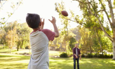 This stock photo shows a father and son tossing a football.