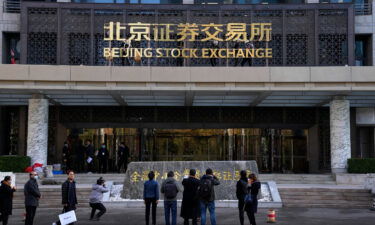 Journalists film workers installing the nameplate of Beijing Stock Exchange on Financial Street in Beijing
