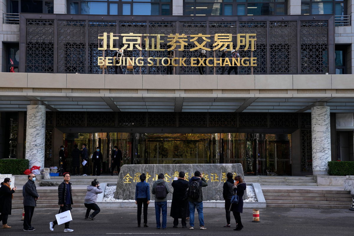 <i>Andy Wong/AP</i><br/>Journalists film workers installing the nameplate of Beijing Stock Exchange on Financial Street in Beijing