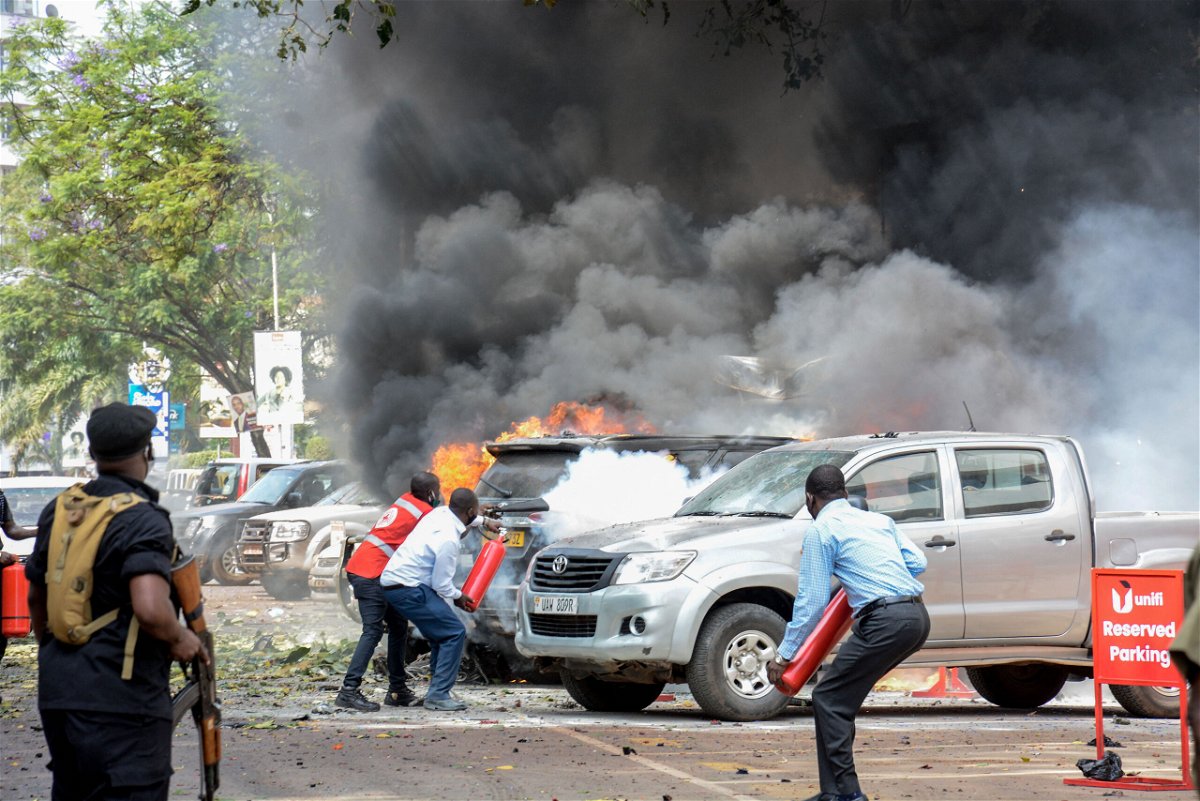 <i>Ivan Kabuye/AFP/Getty Images</i><br/>People extinguish fire on cars caused by a bomb explosion near Parliament building in Kampala