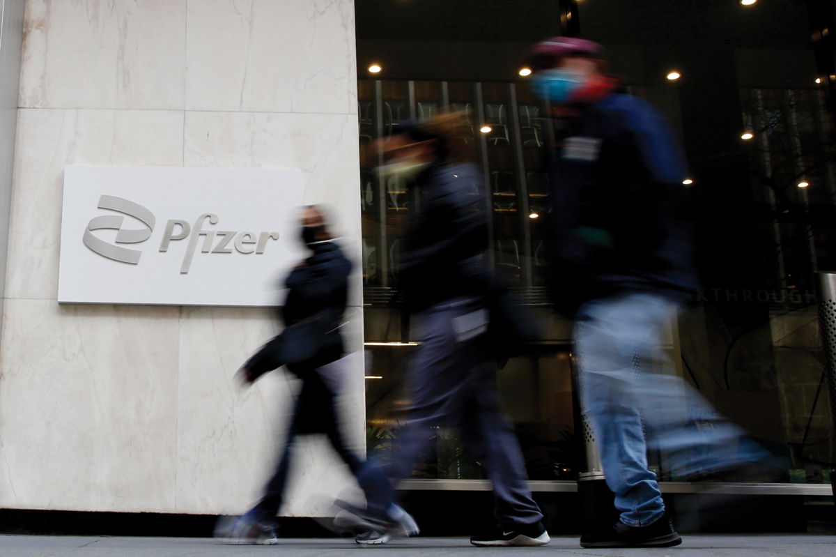 <i>John Smith/VIEWpress/Getty Images</i><br/>Shares of drug giant Pfizer surged more than 10% in early trading Friday after the company announced positive test results for an experimental pill it has developed to fight Covid-19. People are shown here walking in front of Pfizer sign at Pfizer World Headquarters on March 23