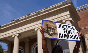 A demonstrator holds a sign at the Glynn County Courthouse as jury selection begins in the trial of the shooting death of Ahmaud Arbery on October 18