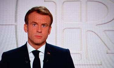 Macron appears on a TV screen as he addresses to the nation on Covid-19 and reforms in Paris on November 9