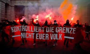 Crowds shout slogans and light flares during a demonstration against Austria's Covid restrictions as the banner reads: "Control the border. Not your people."
