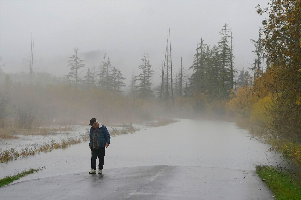 <i>Ted S. Warren/AP</i><br/>A man walking near a road that was closed in Washington due to high water in the latest atmospheric river event.