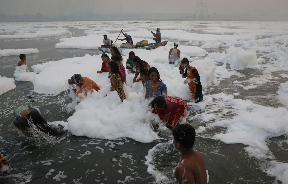 <i>Anushree Fadnavis/Reuters</i><br/>People bathe amidst toxic foam covering the Yamuna river on a smoggy morning in New Delhi