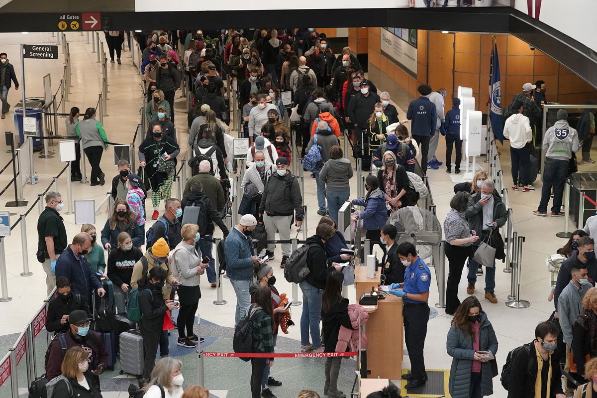 <i>Ted S. Warren/AP</i><br/>Travelers wear masks as they wait in a line for a TSA security check