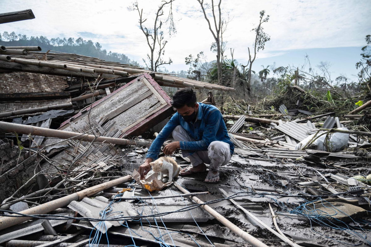<i>Juni Kriswanto/AFP/Getty Images</i><br/>A man salvages some of his belongings from his damaged home in Lumajang on December 8.