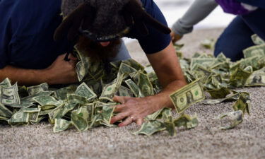 A teacher shovels dollar bills into his shirt during the "Dash for Cash" promotion at a Sioux Falls Stampede game.