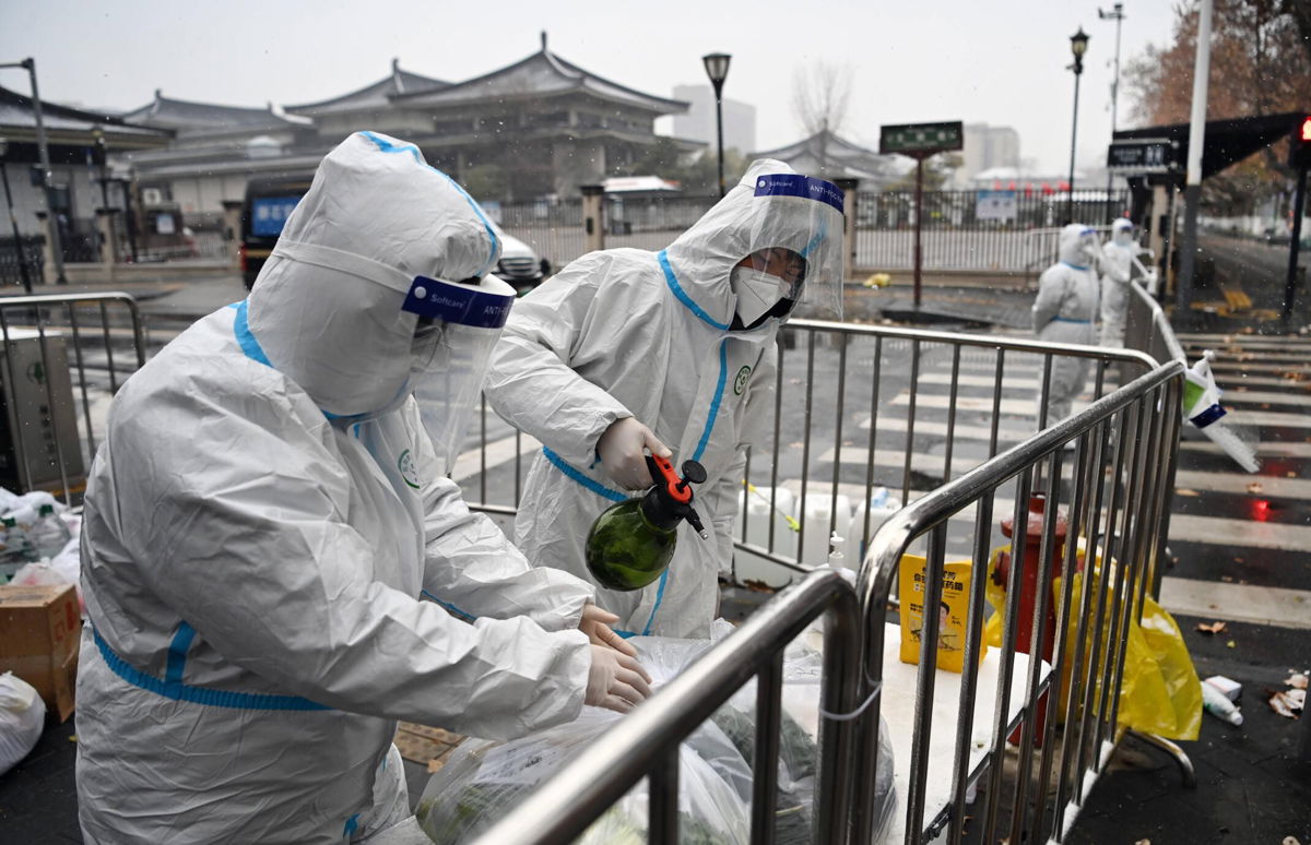 <i>Chine Nouvelle/SIPA/Shutterstock</i><br/>China tightens Xi'an lockdown as city reports highest daily Covid-19 cases in nearly 2 years. Staff members disinfect packed vegetables at a residential area under quarantine in Xi'an on December 25.