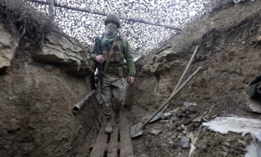 Ukrainian soldiers walks under a camouflage net in a trench on the line of separation from pro-Russian rebels near Debaltsevo