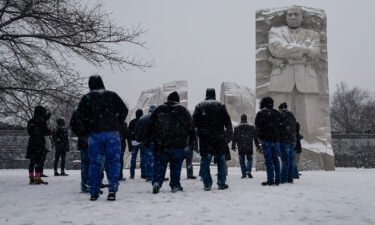 Visitors look to the Martin Luther King Jr. Memorial as snow falls in Washington
