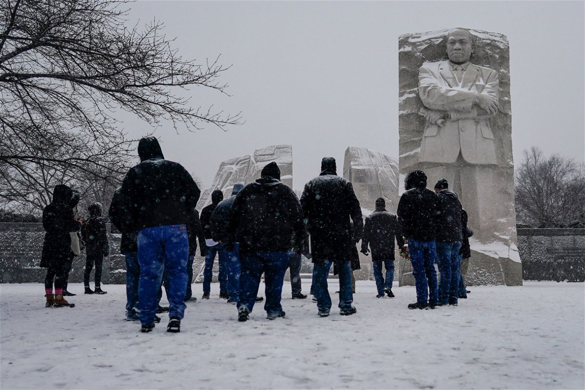 <i>Carolyn Kaster/AP</i><br/>Visitors look to the Martin Luther King Jr. Memorial as snow falls in Washington