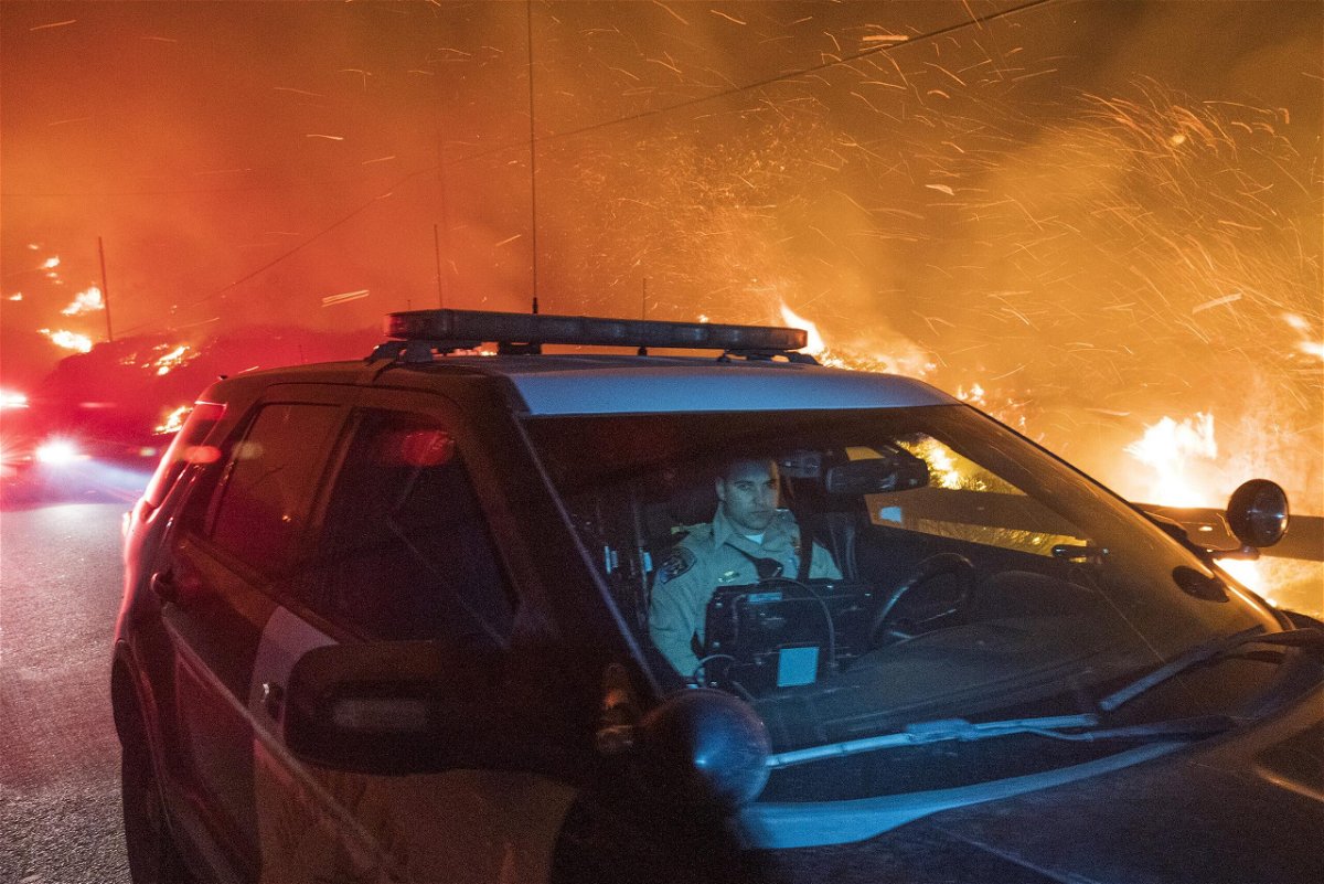 <i>Nic Coury/AP</i><br/>A California Highway Patrol officer drives south on Highway 1 as the Colorado Fire burns near Big Sur