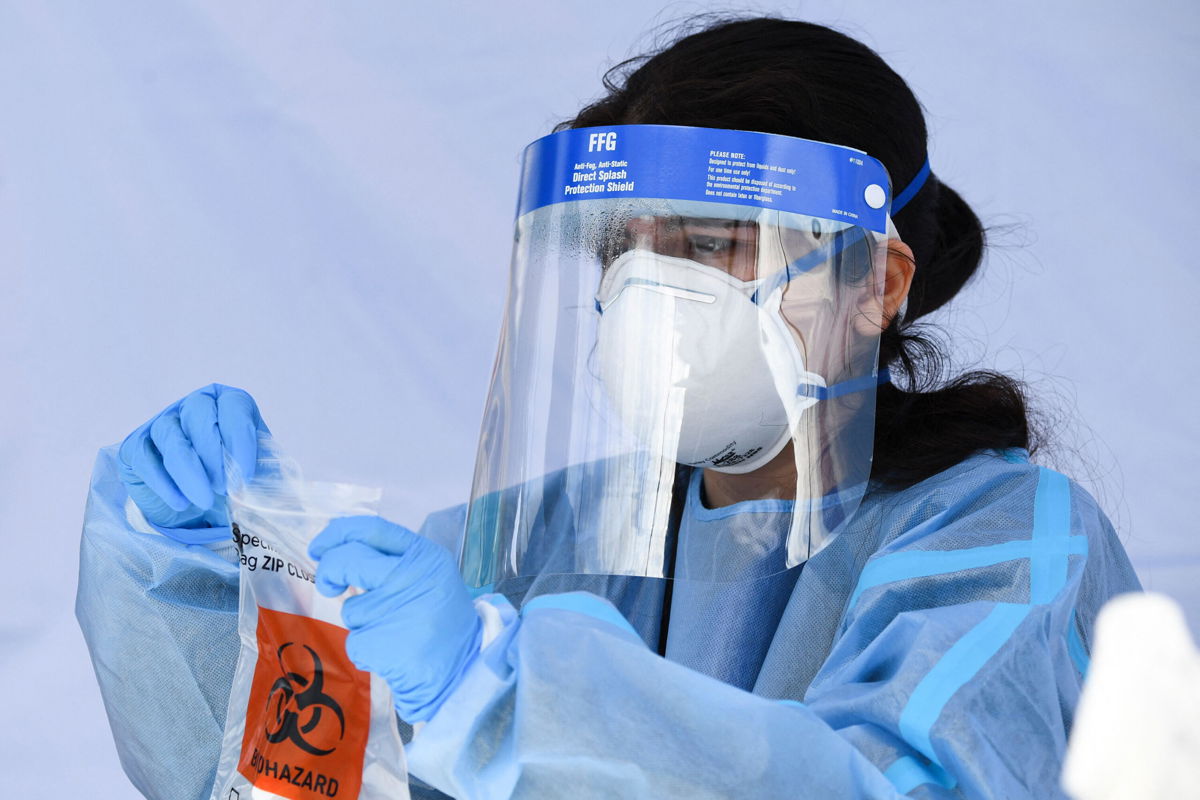 <i>Patrick T. Fallon/AFP/Getty Images</i><br/>A healthcare worker places a Covid-19 PCR test vial into a bag for transportation at a Reliant Health Services testing site in Hawthorne