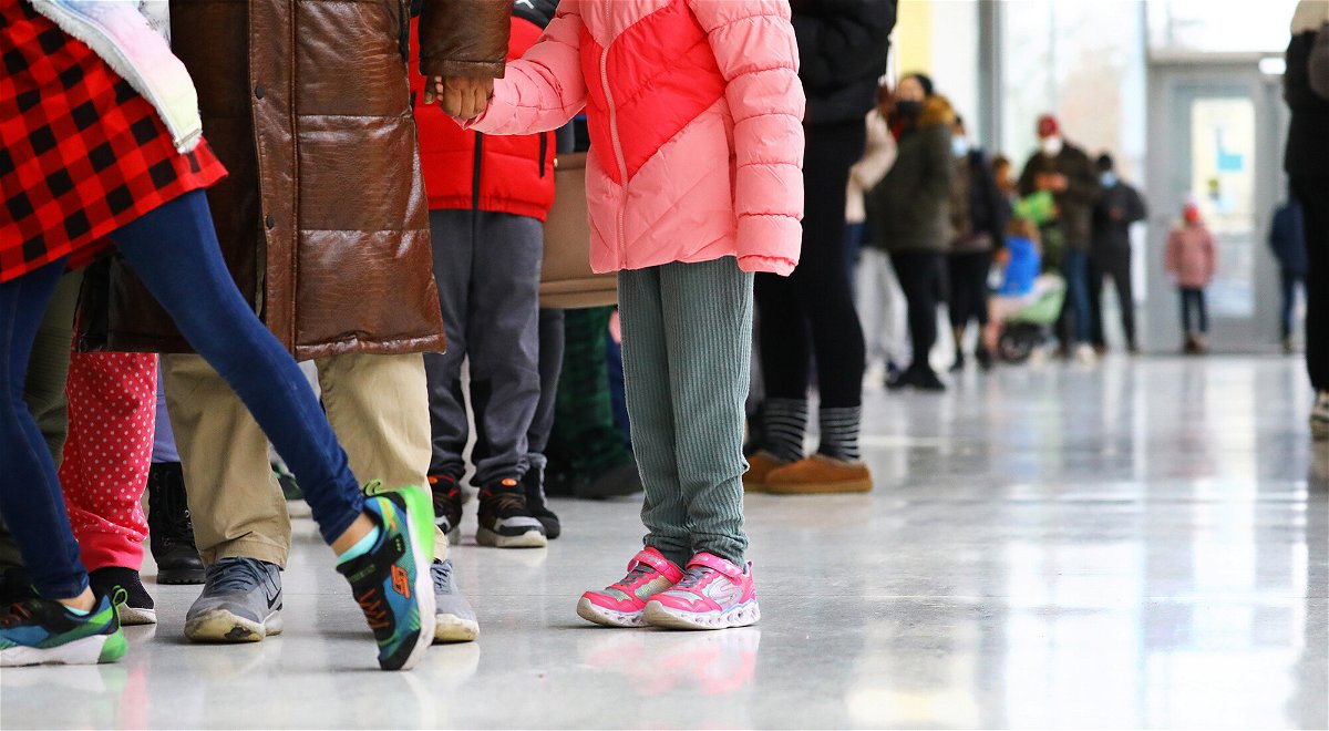 <i>Pat Greenhouse/The Boston Globe/Getty Images</i><br/>Omicron is the latest disaster for working parents. Cambridge students are seen here waiting in line at King Open Elementary School with their parents to be tested for the COVID-19 virus.