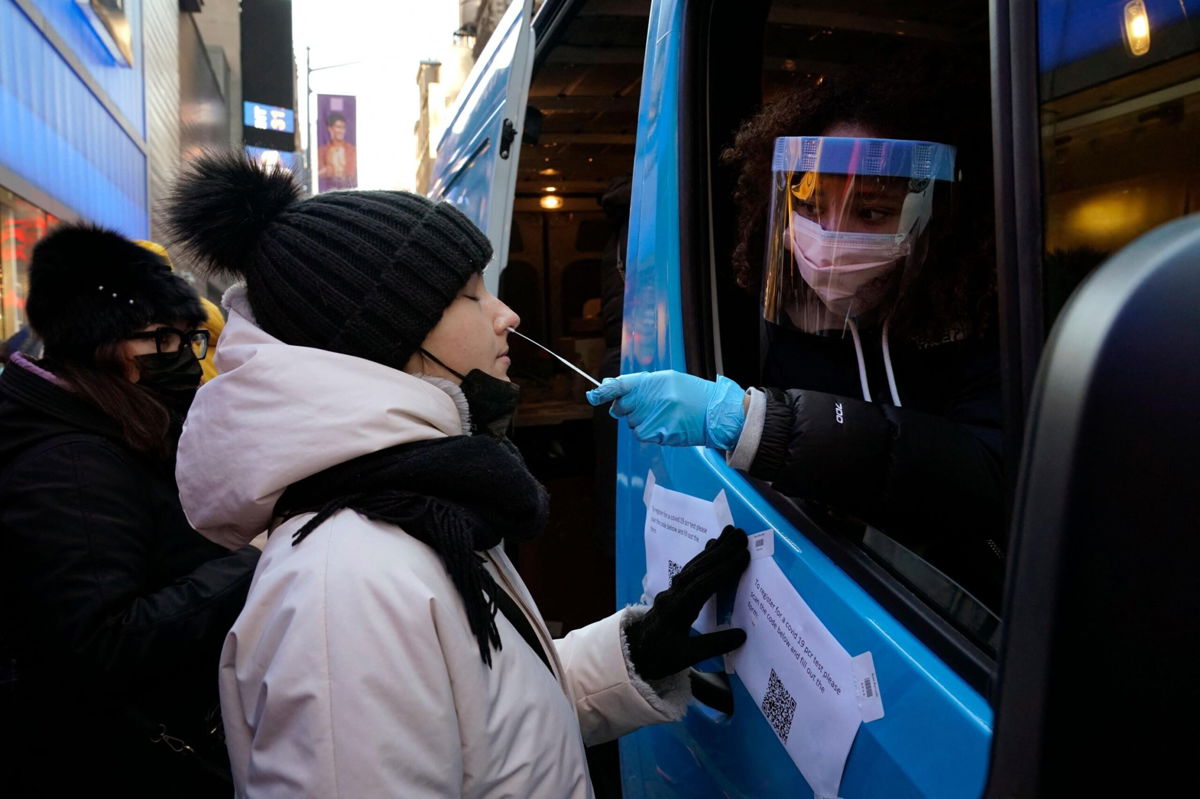<i>TIMOTHY A. CLARY/AFP/AFP via Getty Images</i><br/>People get tested at a mobile Covid-19 testing van in Times Square on January 4