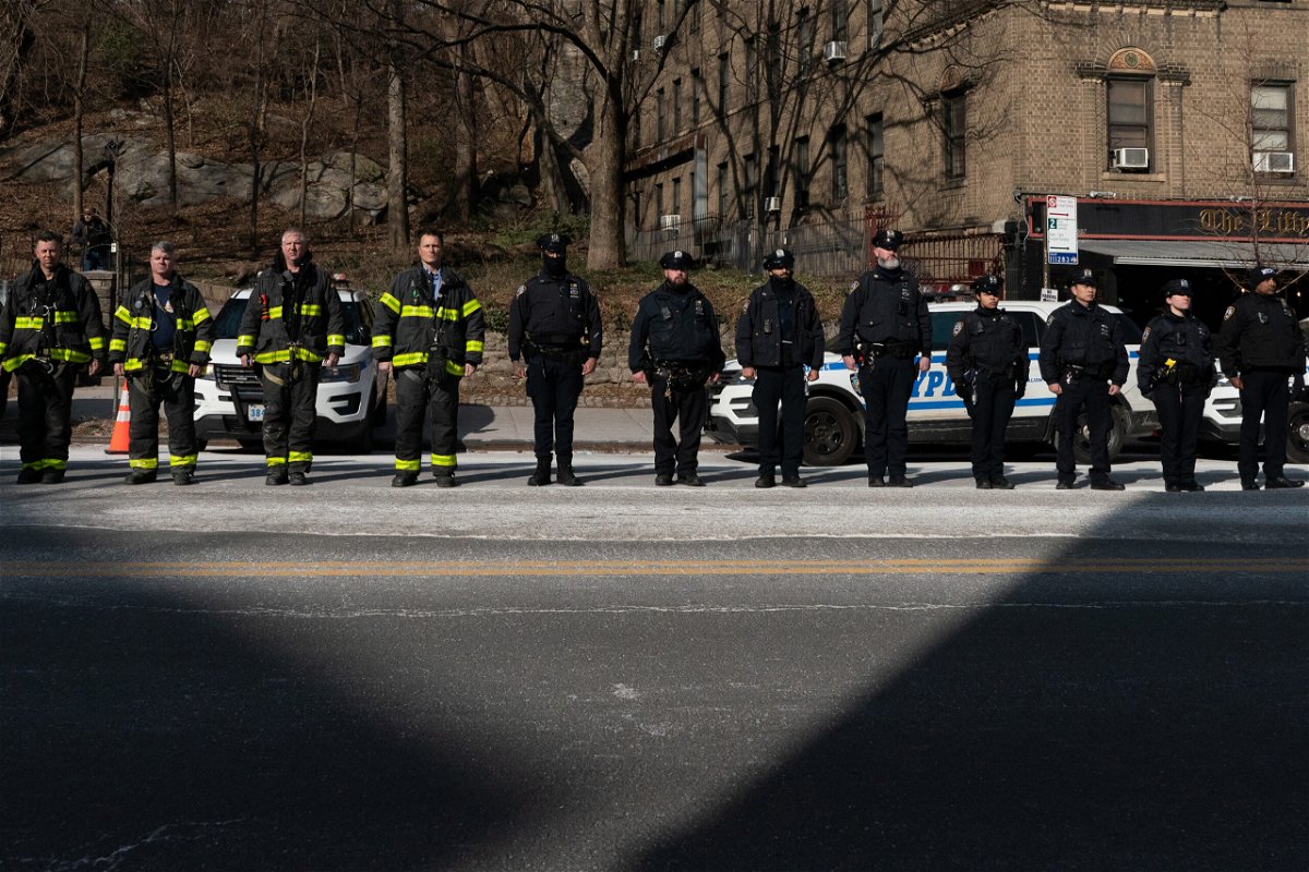 <i>David Dee Delgado/Getty Images</i><br/>New York City police officers and firemen stand at attention as they await the remains of Police Officer Jason Rivera to be brought to the funeral home on January 23 in New York City.