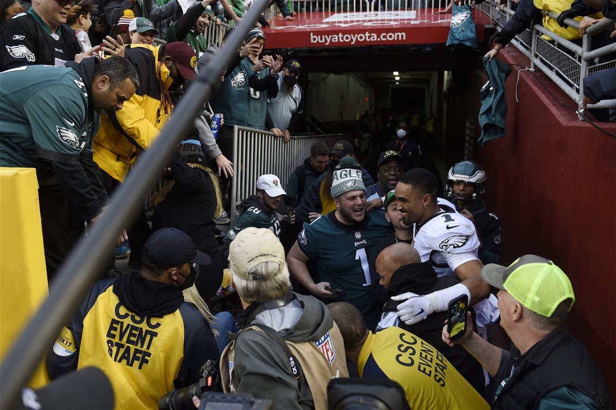 <i>Greg Fiume/Getty Images</i><br/>Jalen Hurts #1 of the Philadelphia Eagles celebrates with fans who fell onto the ground after a railing collapsed following the win over the Washington Football Team 20-16 at FedExField on January 2